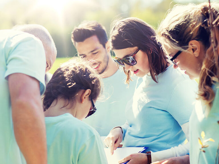 group of teenage volunteers planting trees in park