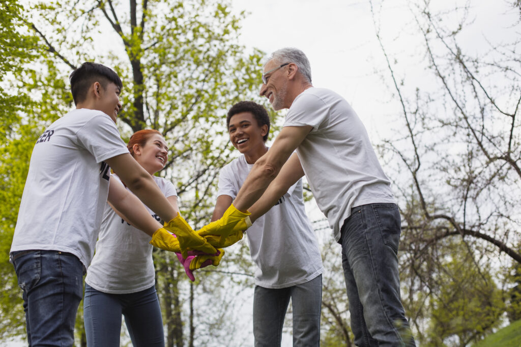 Team spirit. Low angle of optimistic vigorous volunteers standing and holding hands together