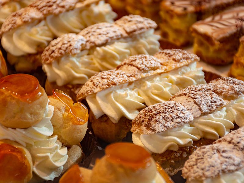 Freshly baked stuffed sweet pastries Orange Lactee and Dome Citron with fruits in traditinal French bakery