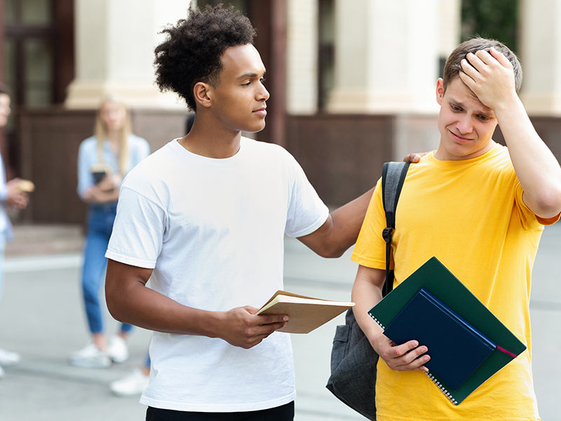 Teenage guy consoling friend over bad exam result