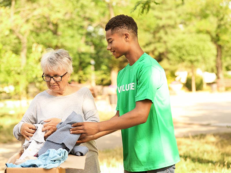 teenage boy helping senior citizen at clothing drive