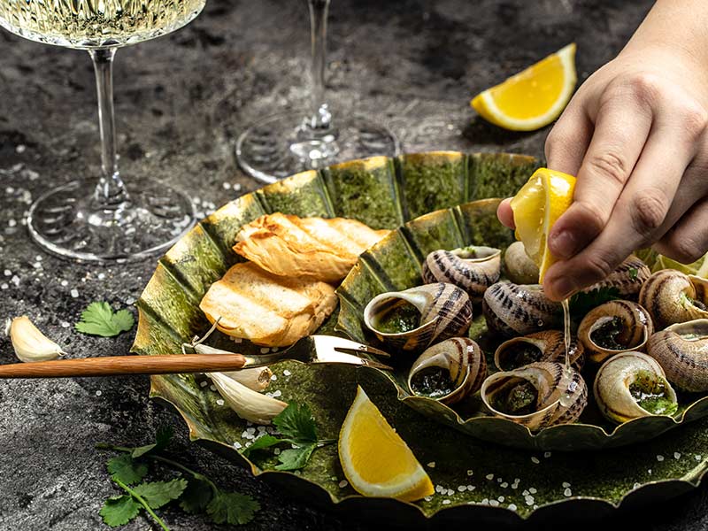 Delicious cooked sea escargo snails with herbs, butter, garlic