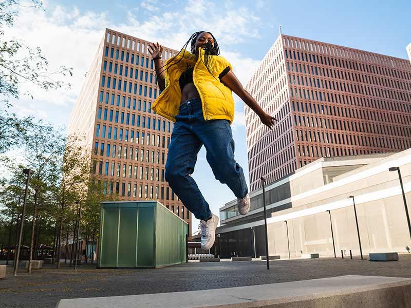 Young urban teenager jumping on street acting independent