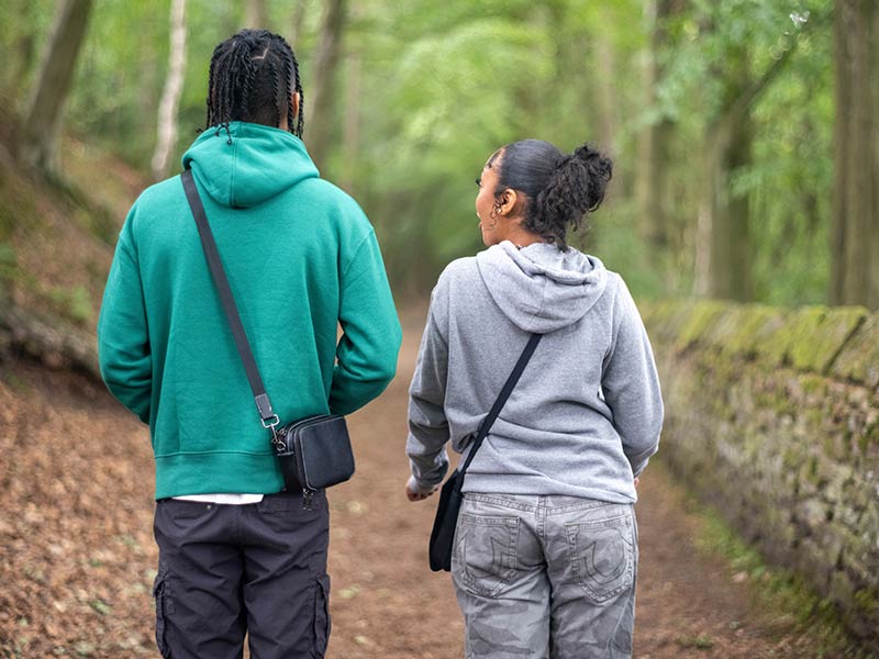 Teenage (16-17) girl and boy in forest, rear view