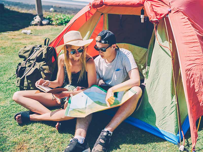 traveling teens looking at a map in their tent